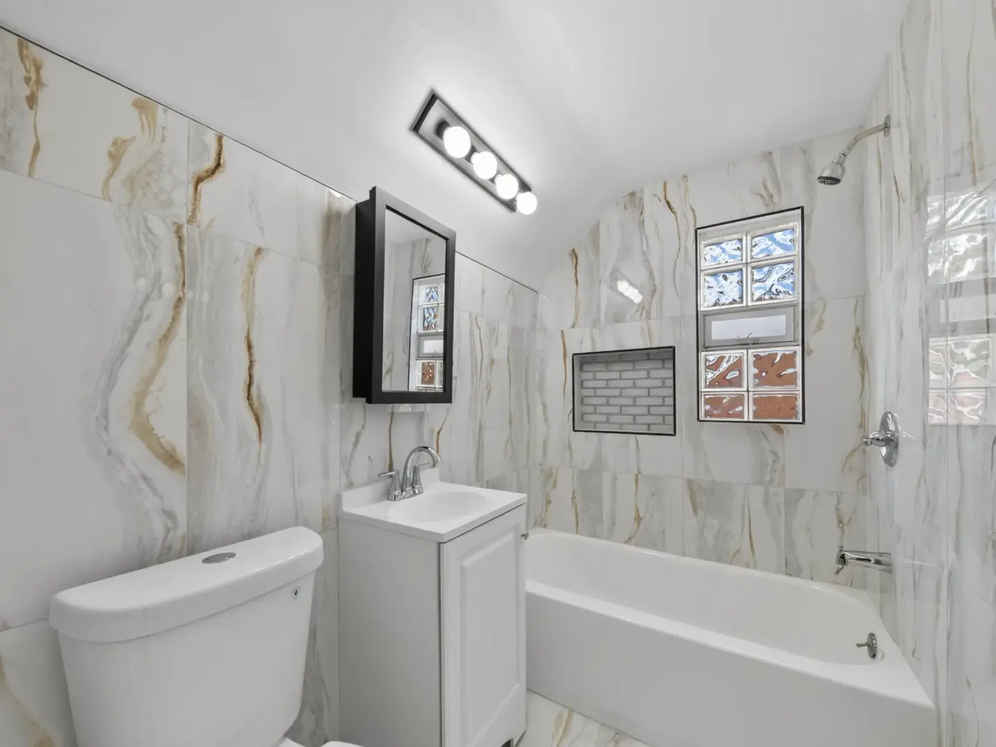 13527 Winthrop Street — renovated bathroom with marble-look wall tile, bathtub, and vanity in Detroit, Michigan