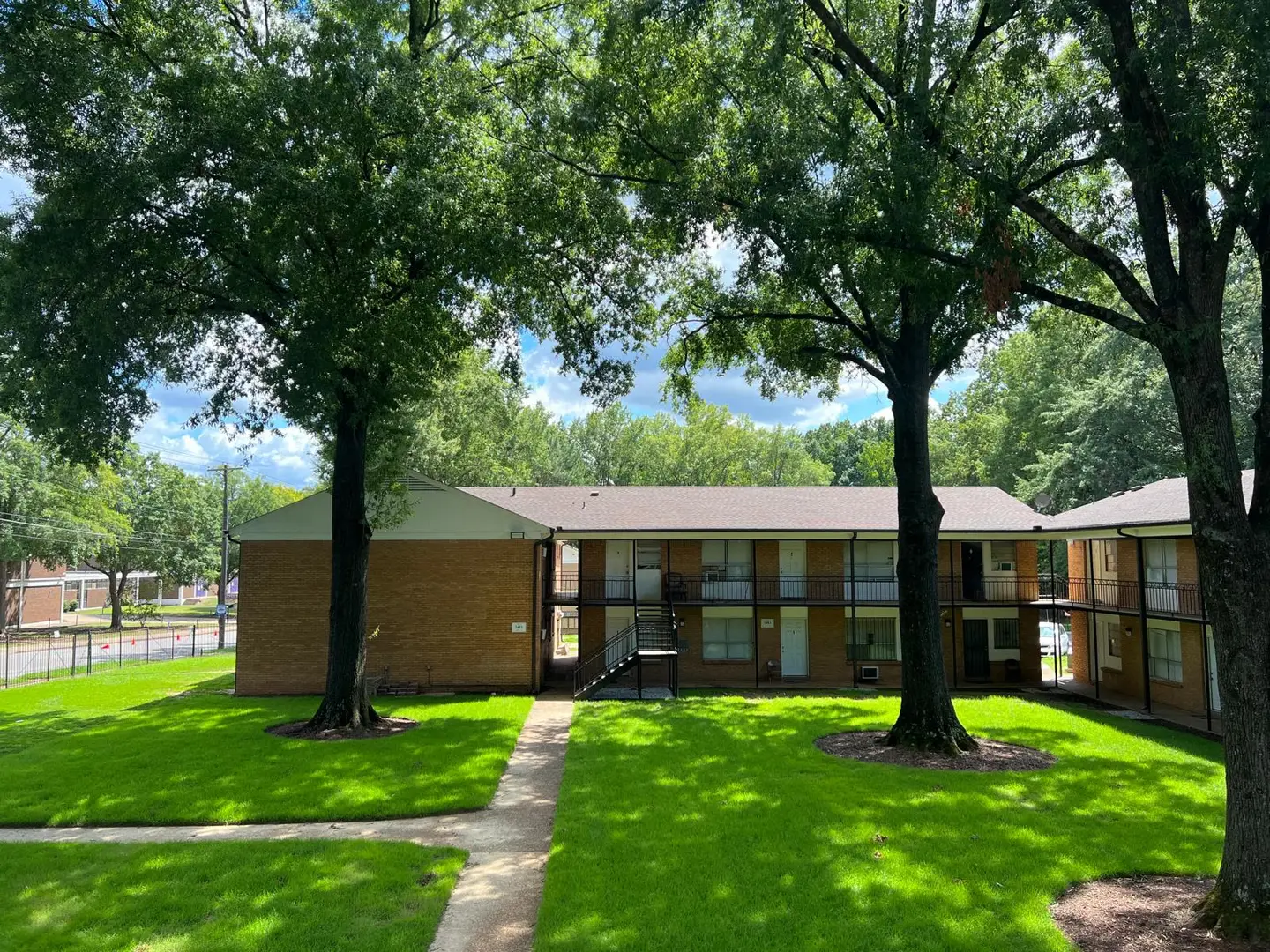 Grand Oaks apartments — brick two-storey building framed by oak trees and lawn in Memphis, Tennessee